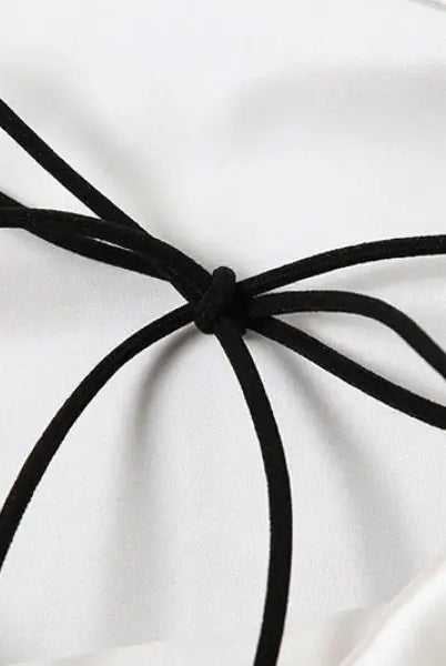 Black cord tie accentuating the elegant backless lace split dress on white fabric