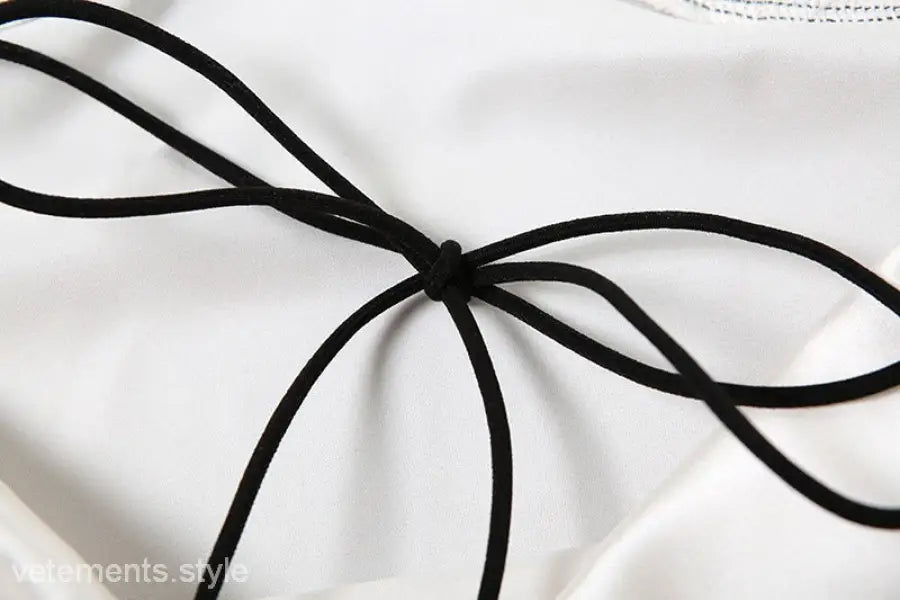 Black cord tie accentuating the elegant backless lace split dress on white fabric