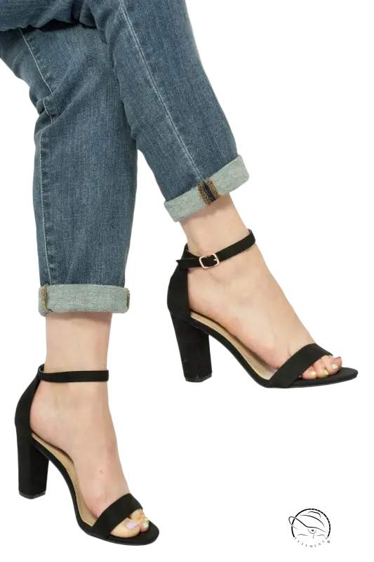 Stylish black heeled sandals with adjustable ankle strap on cuffed jeans