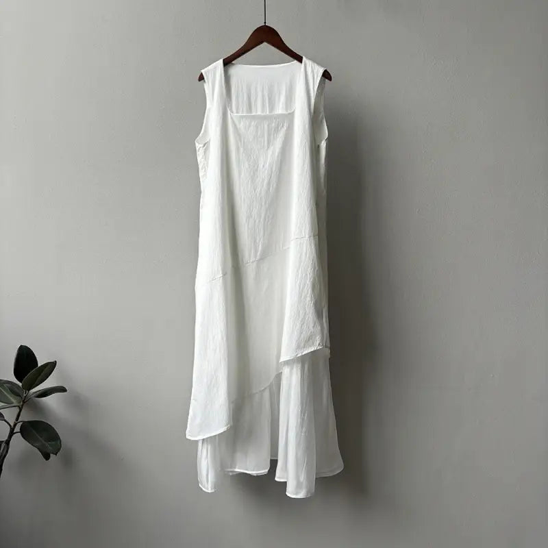 White sleeveless hem stitching dress with asymmetrical layered hem on wooden hanger