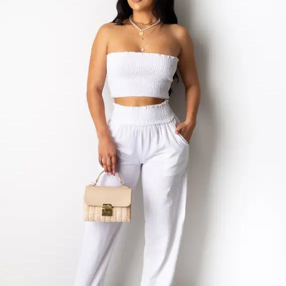 Woman in white crop top and high-waisted pants holding a beige handbag for Berlin summer outfit