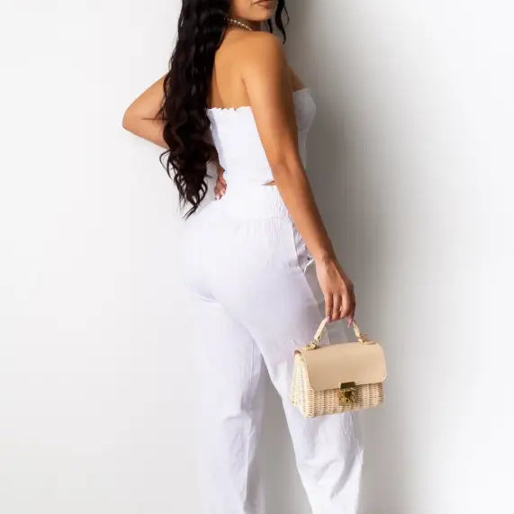 Woman with long dark hair in white summer outfit holding beige handbag for Berlin summer outfit