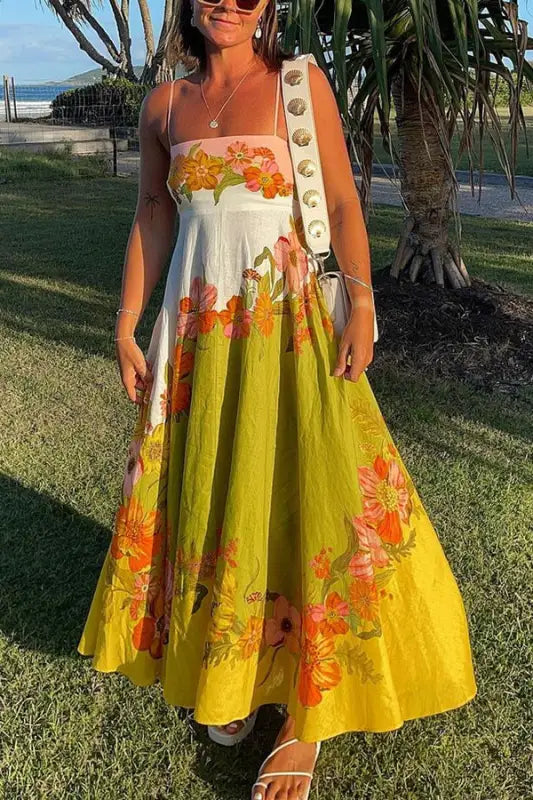 Colorful floral maxi dress with a white bodice and yellow skirt adorned with orange and pink flower patterns.
