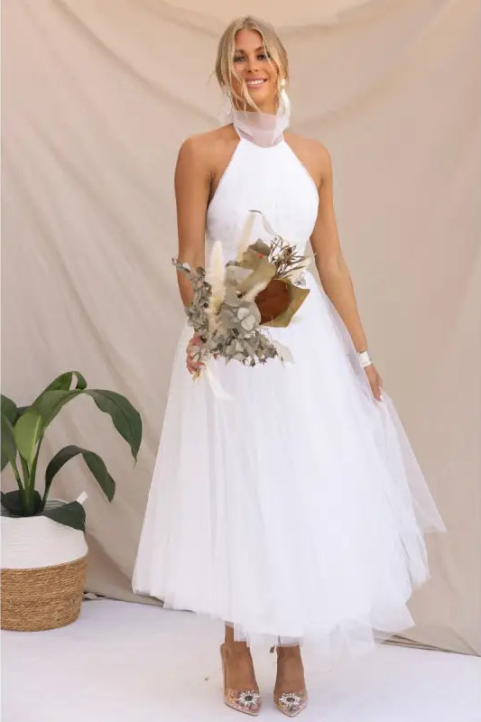 Elegant halter evening dress in mesh and lace worn by woman holding bouquet