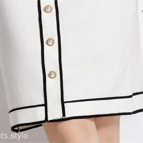 Elegant high rise long sleeve top with short skirt set featuring black trim and gold buttons