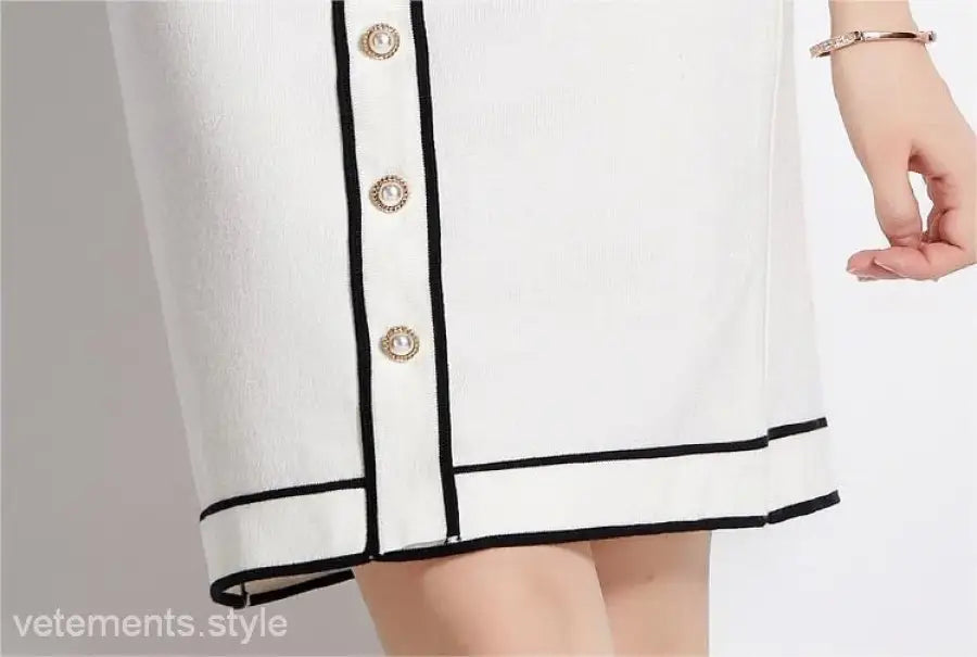 Elegant high rise long sleeve top with short skirt set featuring black trim and gold buttons