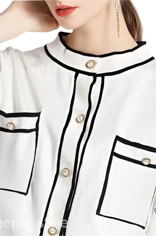 Elegant high rise long sleeve top with white blouse, black trim, decorative buttons, and short skirt set