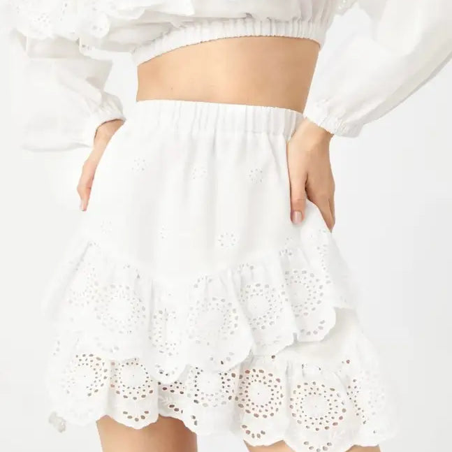White eyelet lace mini skirt with ruffled hem and elastic waistband, ideal with jacquard ultra short crop tops