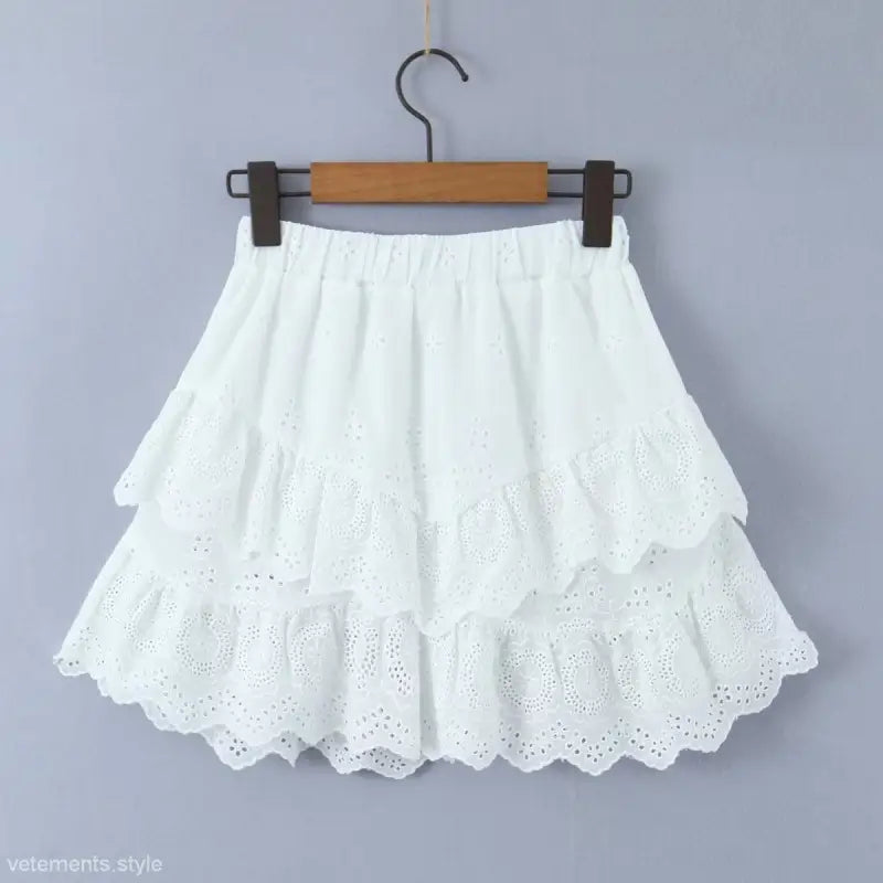 White tiered eyelet lace skirt hanging on a wooden hanger, complements Jacquard Ultra Short high waist crop top