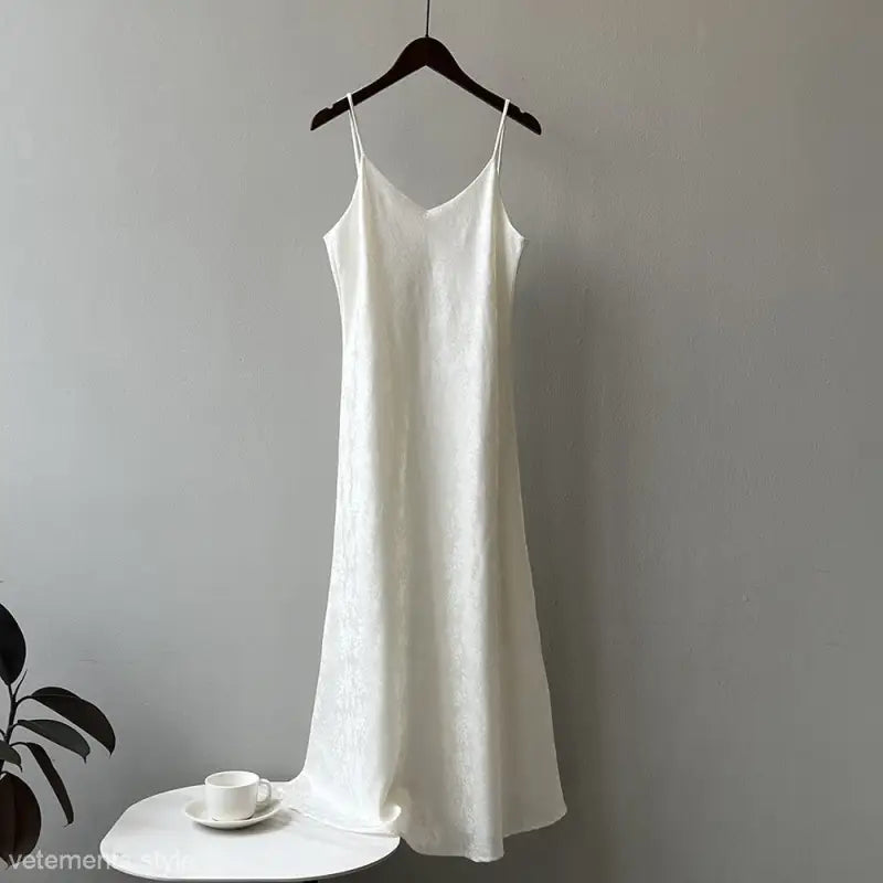 White elegant jacquard V-neck strap dress hanging on a hanger for summer fashion