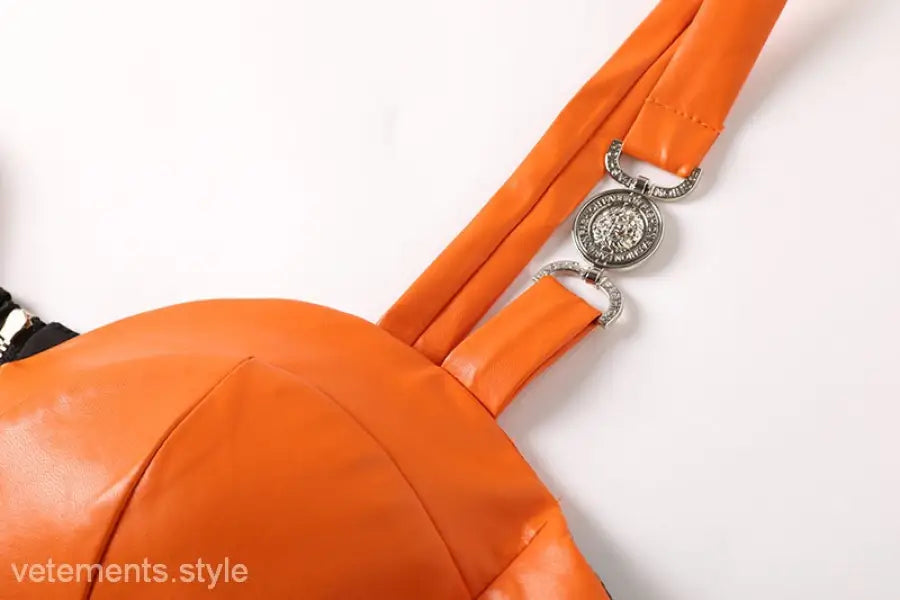 Elegant leather set featuring an orange leather chest wrap with decorative hardware and zipper hip skirt