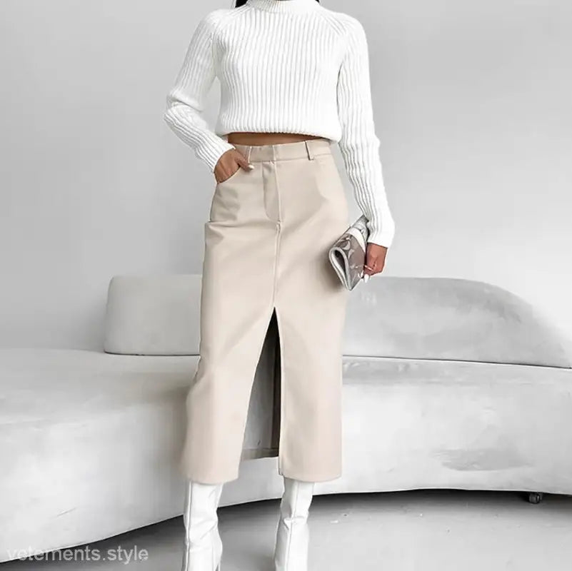 Woman wearing an elegant light khaki fleece leather high waist slit midi skirt with a white sweater