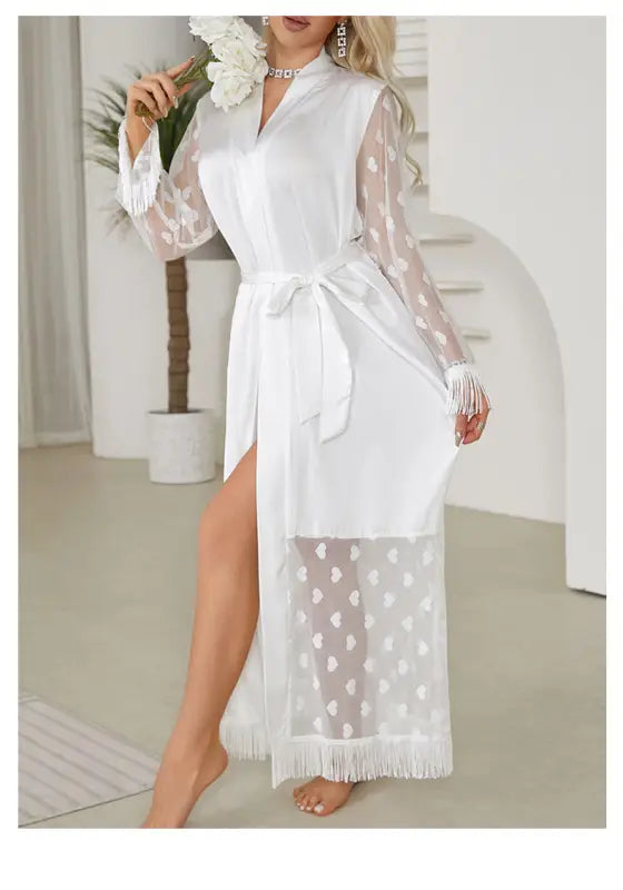 White lace robe with sheer sleeves, a high slit, and fringe details.