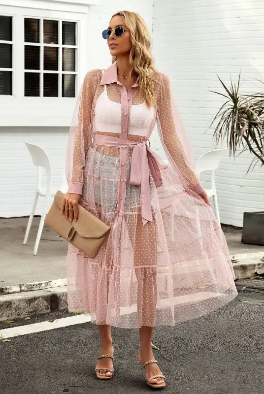 Woman in a sheer pink polka dot summer mesh dress showcasing a long sleeve waist dress design