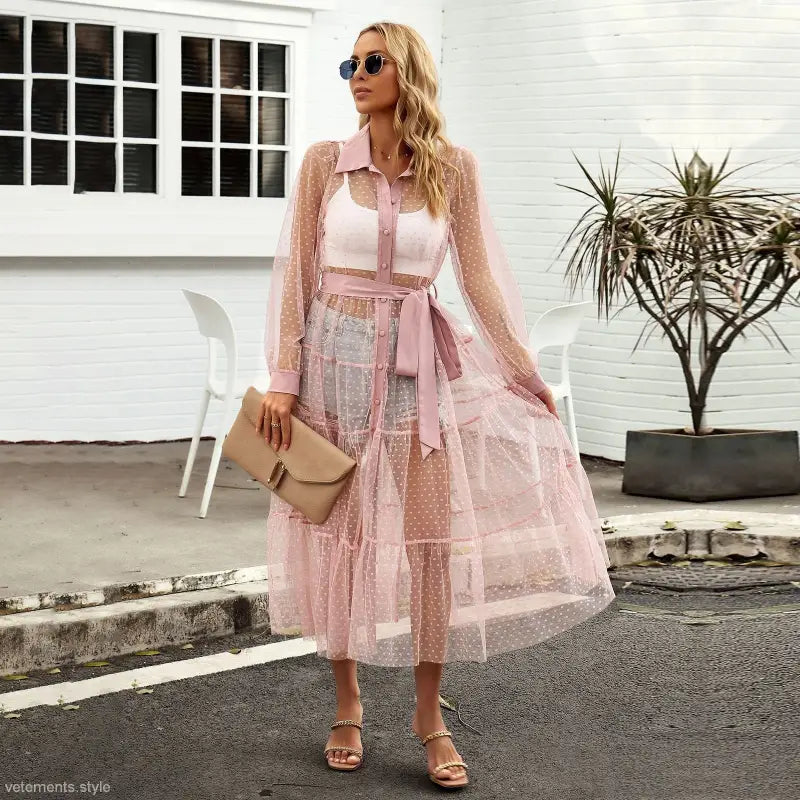 Woman in a sheer pink polka dot summer mesh dress showcasing a long sleeve waist dress design