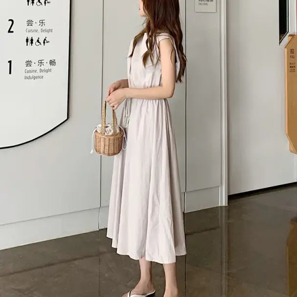 Woman wearing a long white sleeveless dress and carrying a small wicker basket.