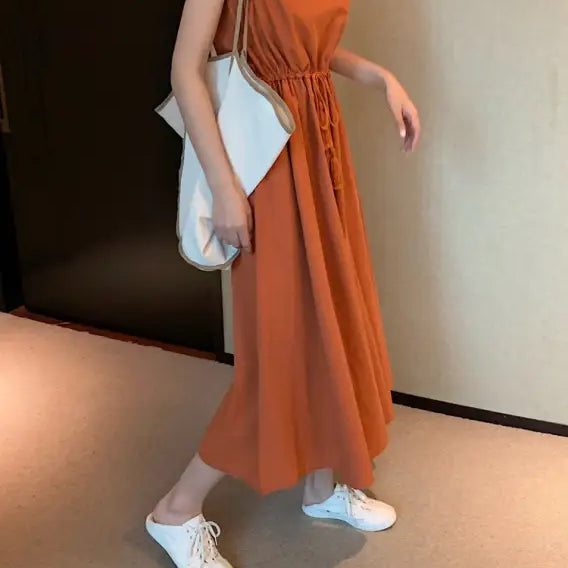 Orange sleeveless maxi dress with a cinched waist.