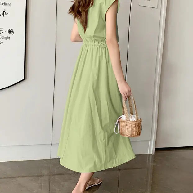 Light green midi dress with cap sleeves and a cinched waist, paired with a small wicker handbag.