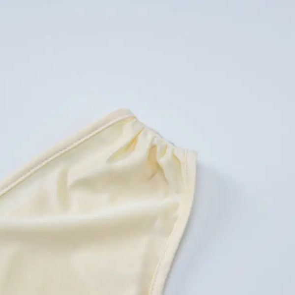 Cream-colored fabric or garment edge with gathered elastic or stitching.