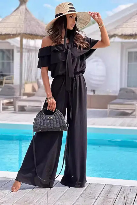 Woman in black shoulder jumpsuit and straw hat showcasing Elegant Off Shoulder Ruffle Jumpsuit
