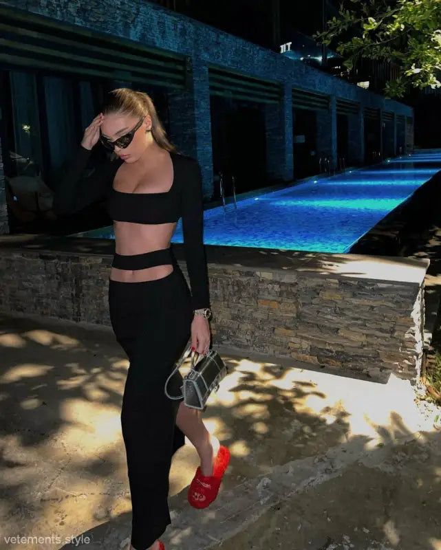 Person in black two-piece athletic outfit by pool, showcasing sexy stretch bandage style