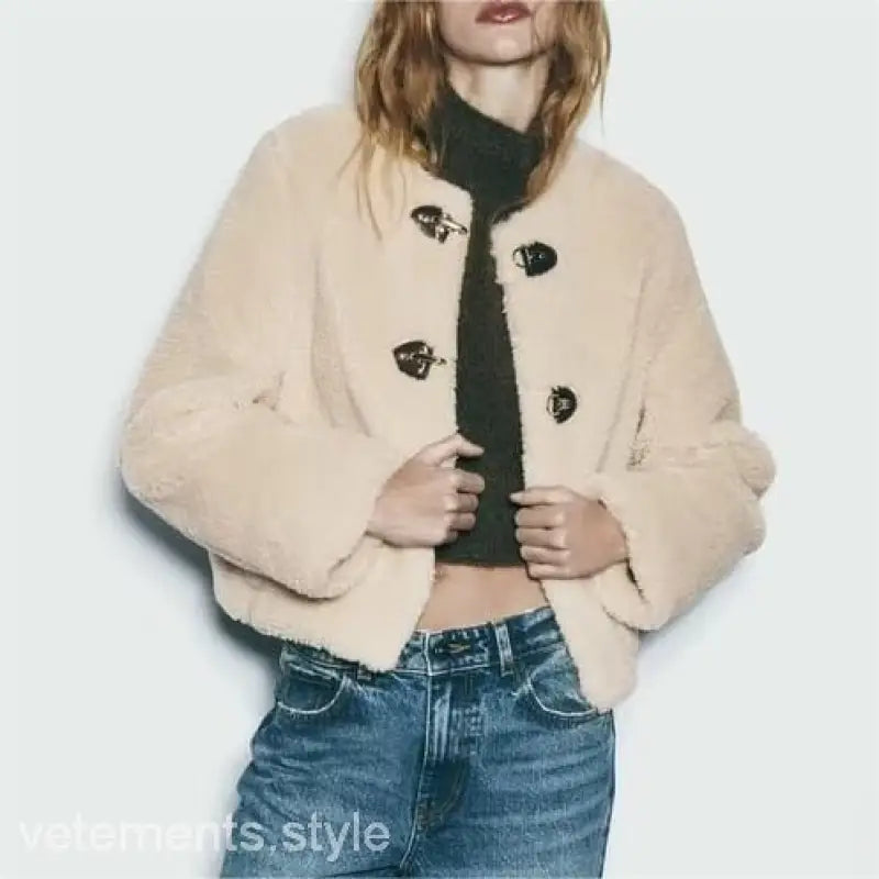 Cream-colored ornament fleece jacket with toggle closures styled over black top and blue jeans