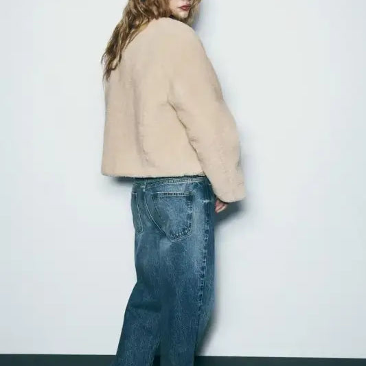 Woman in beige ornament fleece jacket, blue jeans, looking over her shoulder