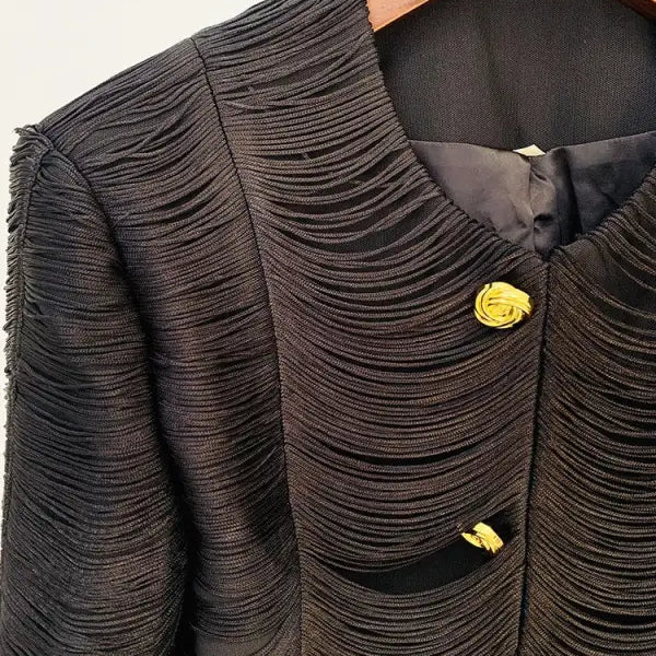 Textured black jacket with yellow rose-shaped buttons hanging on a wooden hanger, stylish tassel short jacket