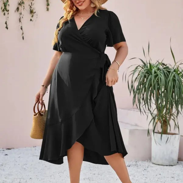 Woman wearing a black wrap dress, sunglasses, and a wide-brimmed straw hat.