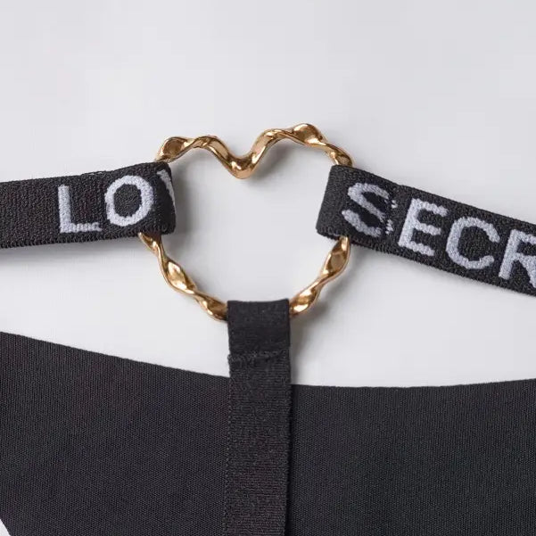 Heart-shaped gold clasp connecting black fabric straps on elegant T-shaped black shaped panties