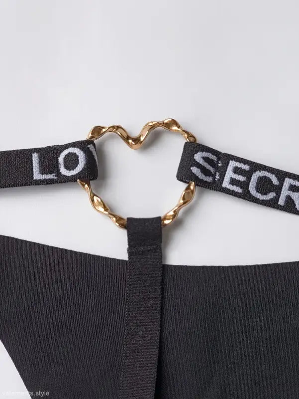 Heart-shaped gold clasp connecting black fabric straps on elegant T-shaped black shaped panties