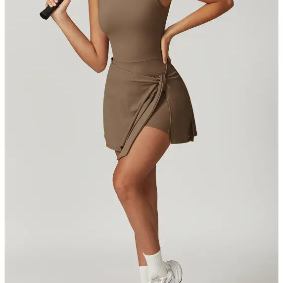 Sleeveless tan dress with a wrapped skirt detail, paired with white sneakers and socks.