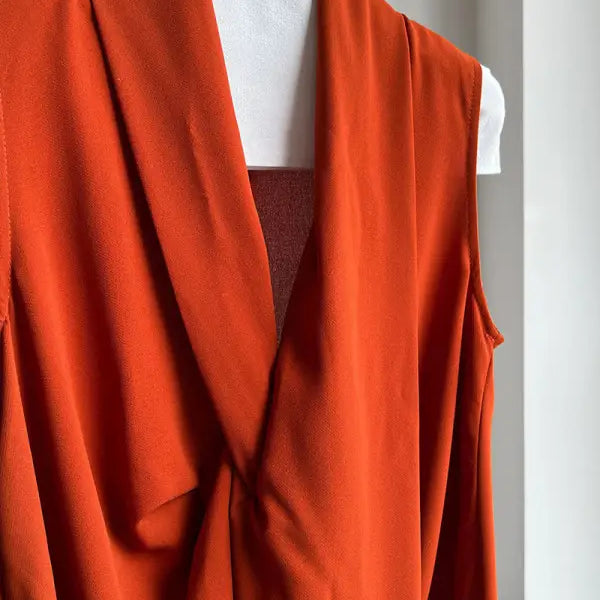 Bright orange draped garment with flowing folds and an open front.