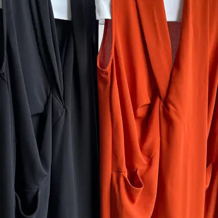 Two sleeveless dresses on hangers, one black and one orange.