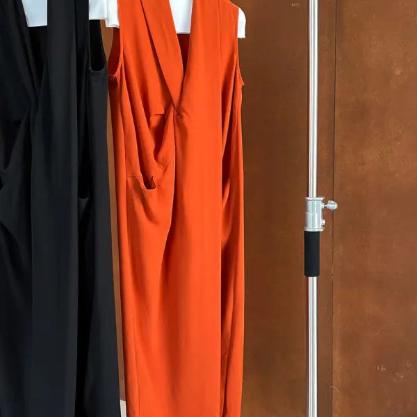 Bright orange sleeveless dress with a plunging neckline hanging on a display.