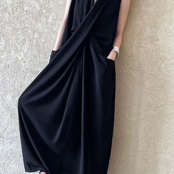 Sleeveless black maxi dress with a draped, wrap-style design and pockets.