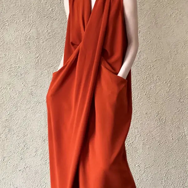 Sleeveless rust-colored maxi dress with a draped, wrap-style design and pockets.