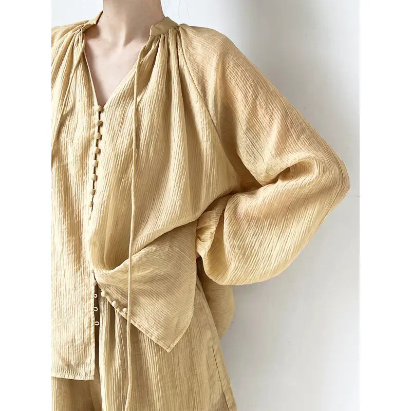 Textured tan blouse with tie neck, ideal for pairing with wide leg shorts for a comfy look