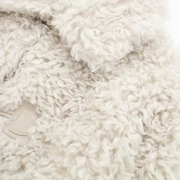 Soft, fluffy off-white material of a winter furry short jacket for nightout occasions