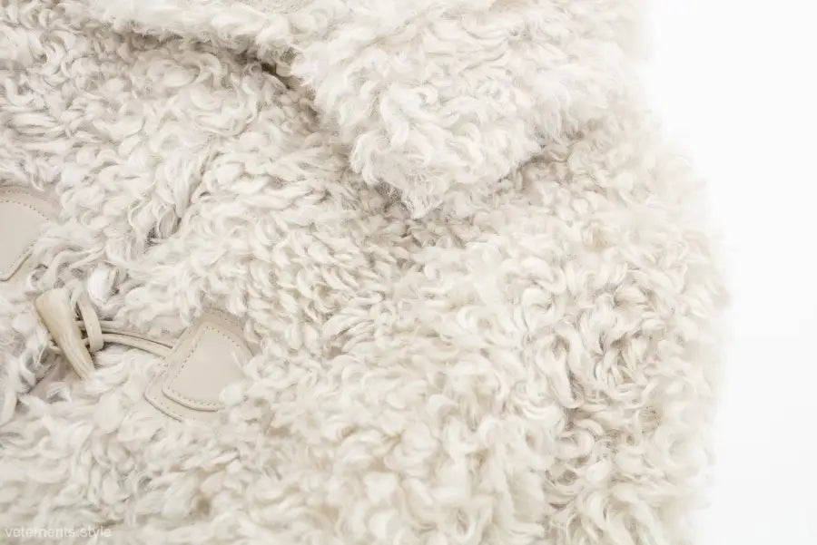 Soft, fluffy off-white material of a winter furry short jacket for nightout occasions