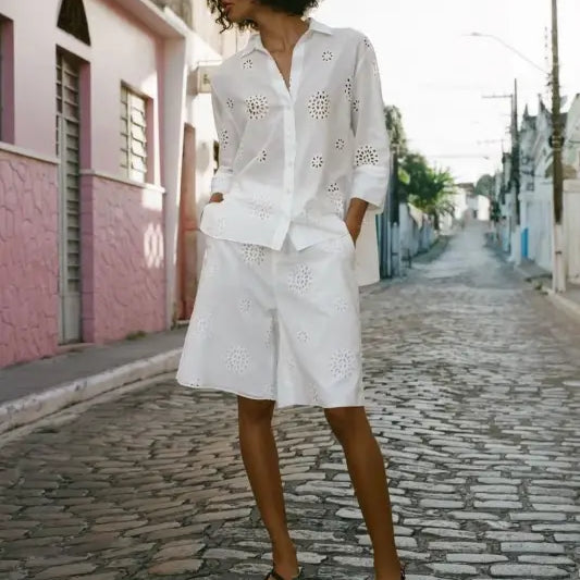 Woman in an all-white high waist casual hollow outfit with eyelet details on a cobblestone street