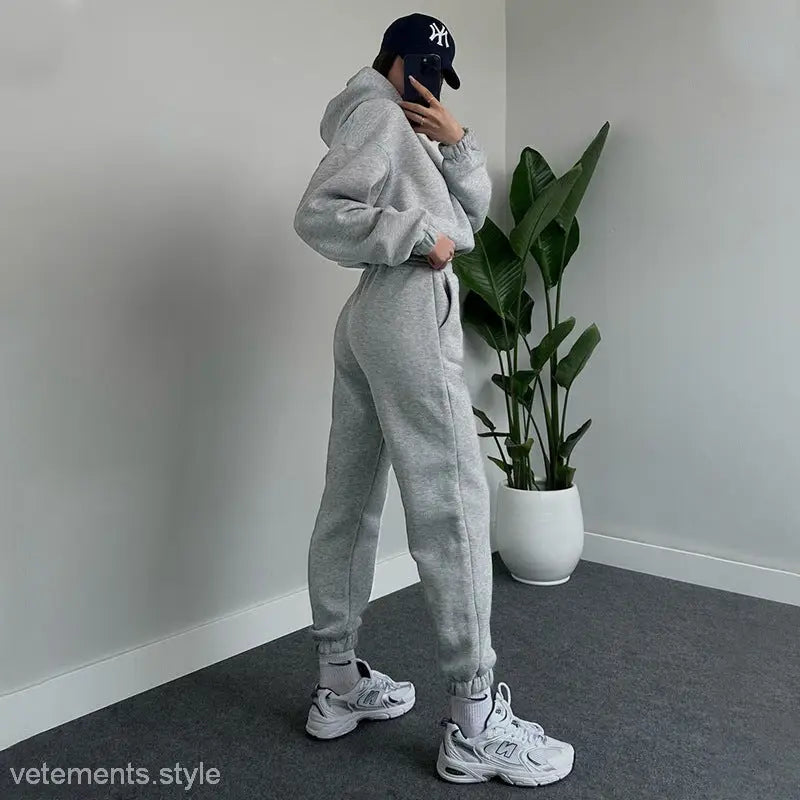 Person in gray hooded long sleeve sweater, New York Yankees cap, white sneakers for casual winter wear