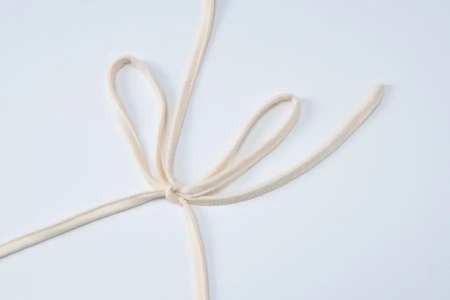 Tied beige fabric straps on lace vest pleated skirt set for a stylish summer look