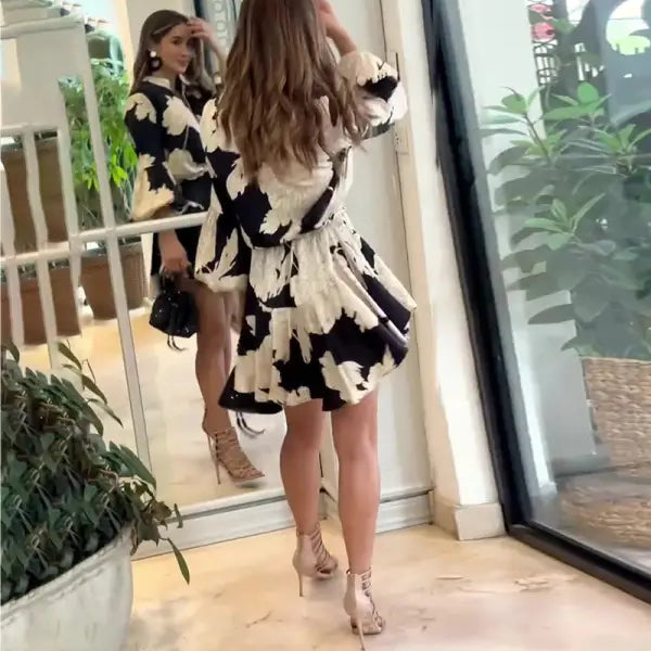 Woman wearing a black and white patterned dress standing in front of a mirror.