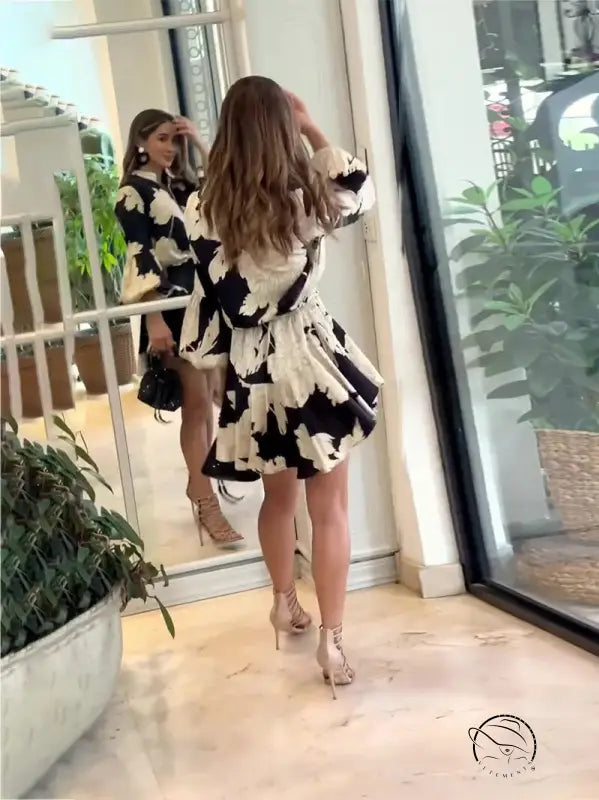 Woman wearing a black and white patterned dress standing in front of a mirror.