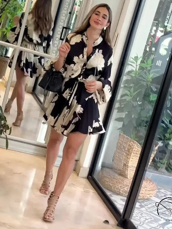 Woman wearing a black and white floral print dress with strappy sandals.