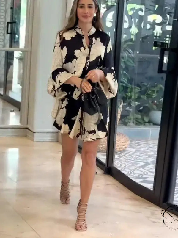 Woman wearing a black and white patterned dress with long sleeves and strappy sandals.