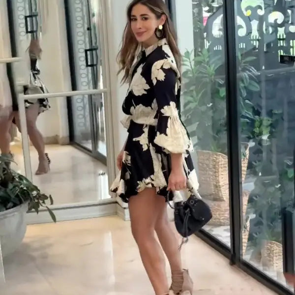 Woman wearing a black and white floral print dress with bell sleeves and high heels.