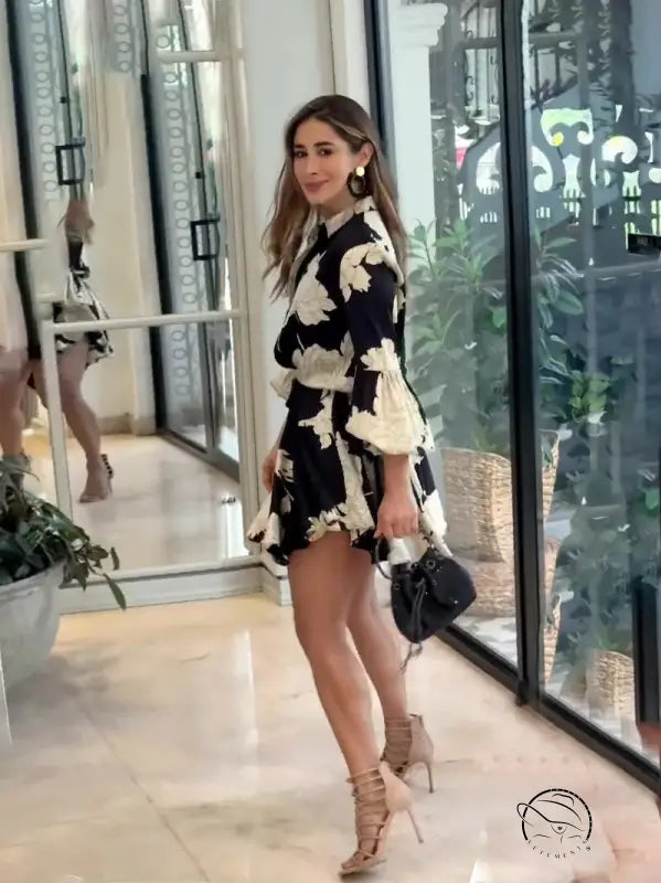 Woman wearing a black and white floral print dress with bell sleeves and high heels.