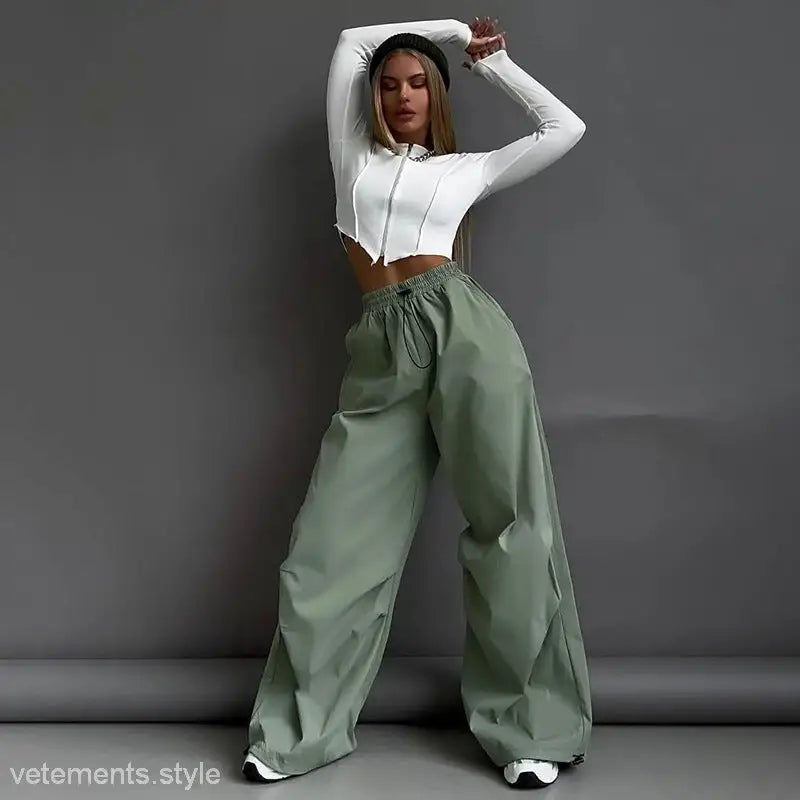 Woman wearing casual cute trousers in light gray with white crop top and green pants